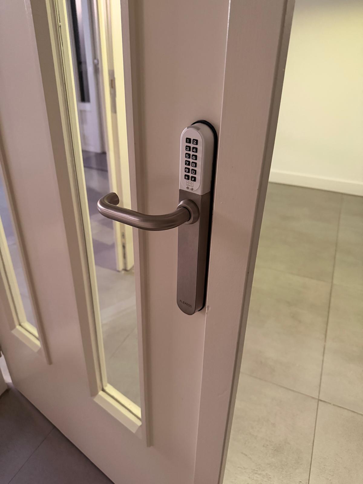 Deurklink met codebediening op een witte deur