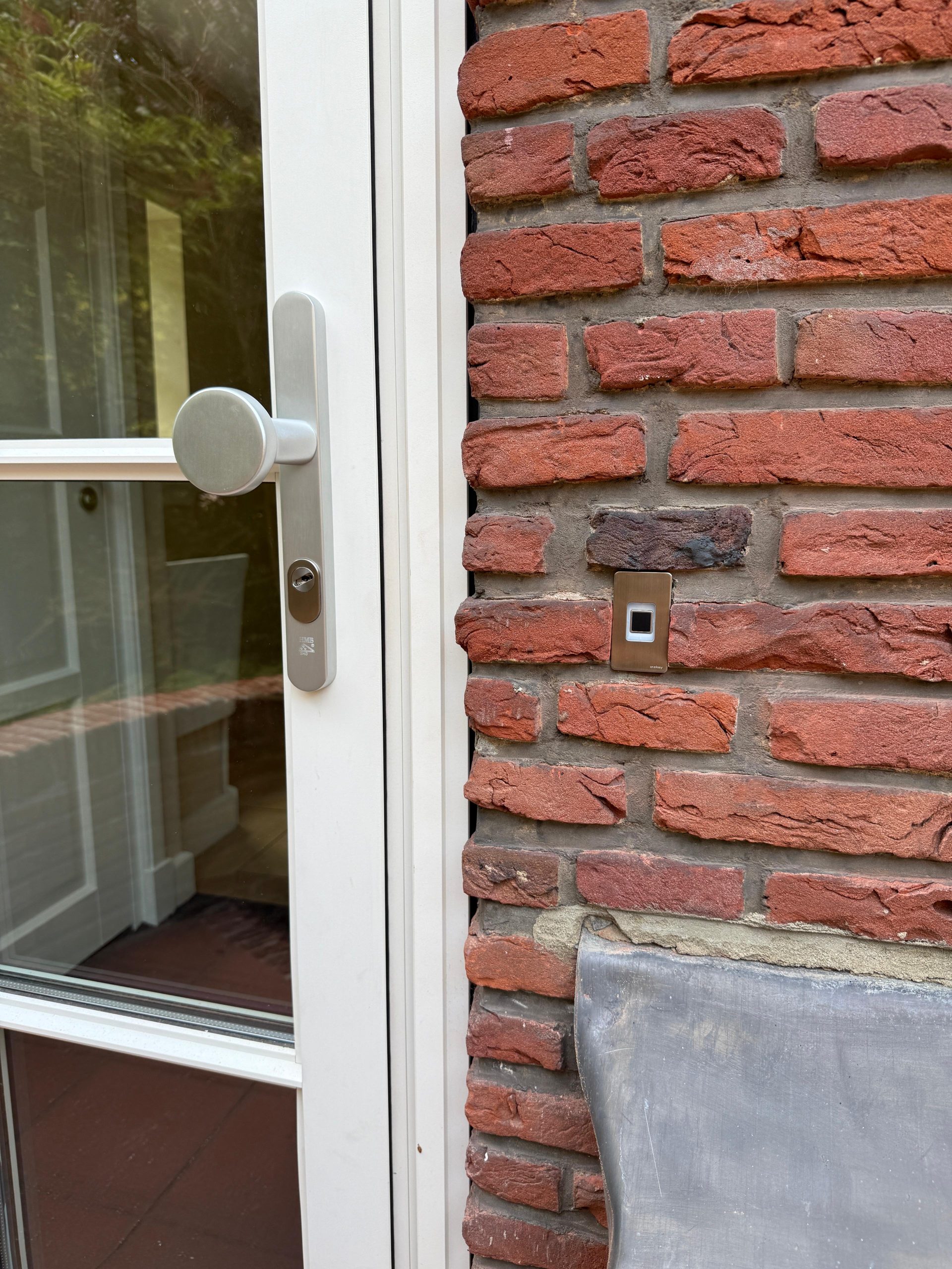 Witte voordeur met veiligheidsbeslag en vingerafdruklezer in de gevel