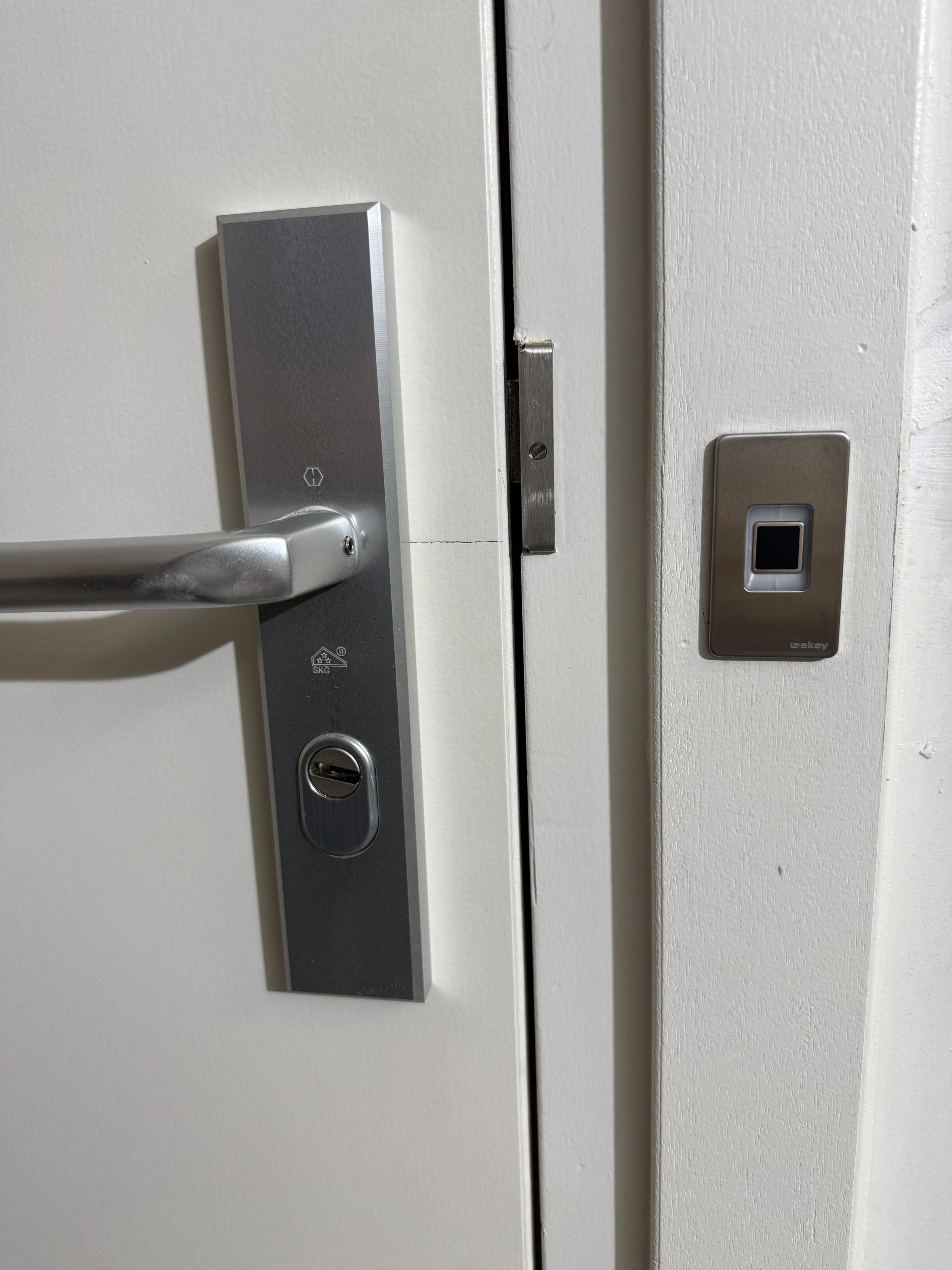 Veiligheidsbeslag en een vingerafdruklezer naast een witte deur